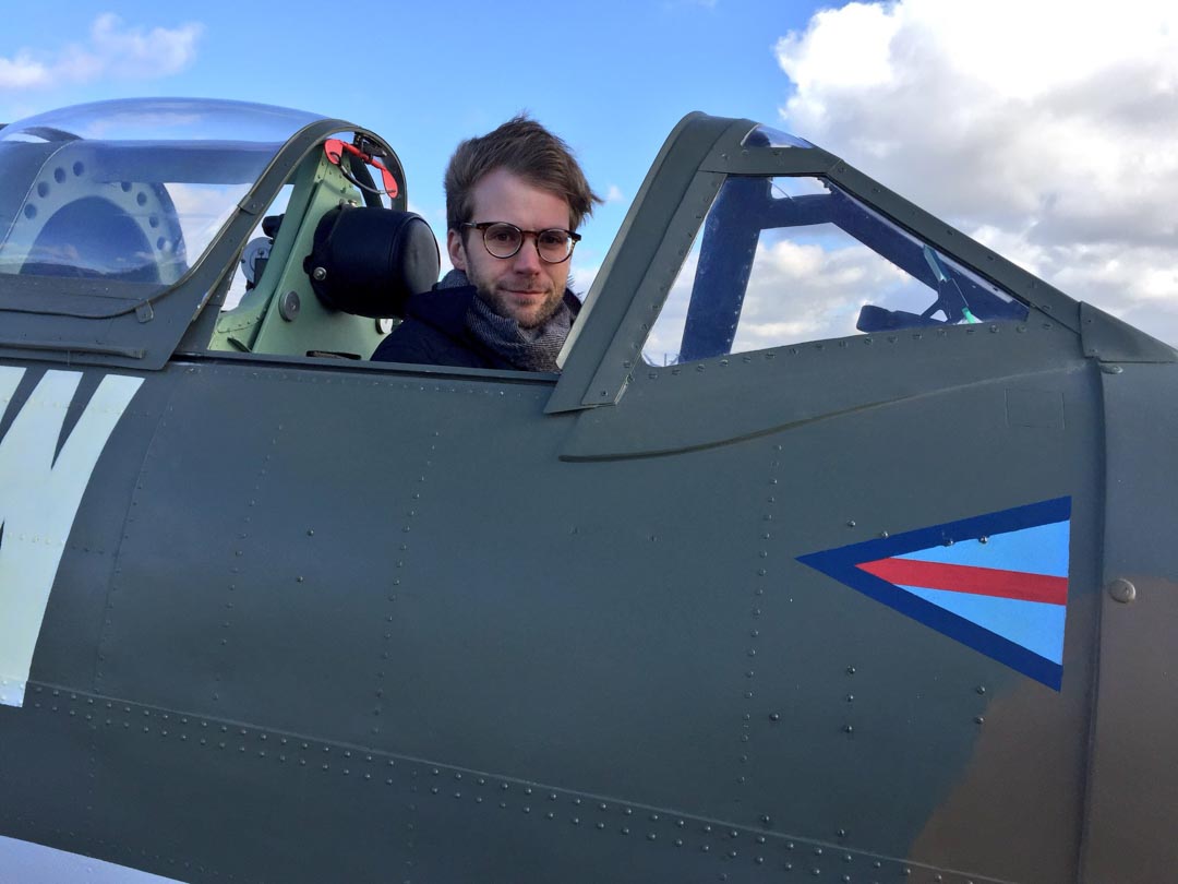 Anthony Woodley Creative Director Aviation Filming sitting in Spitfire cockpit